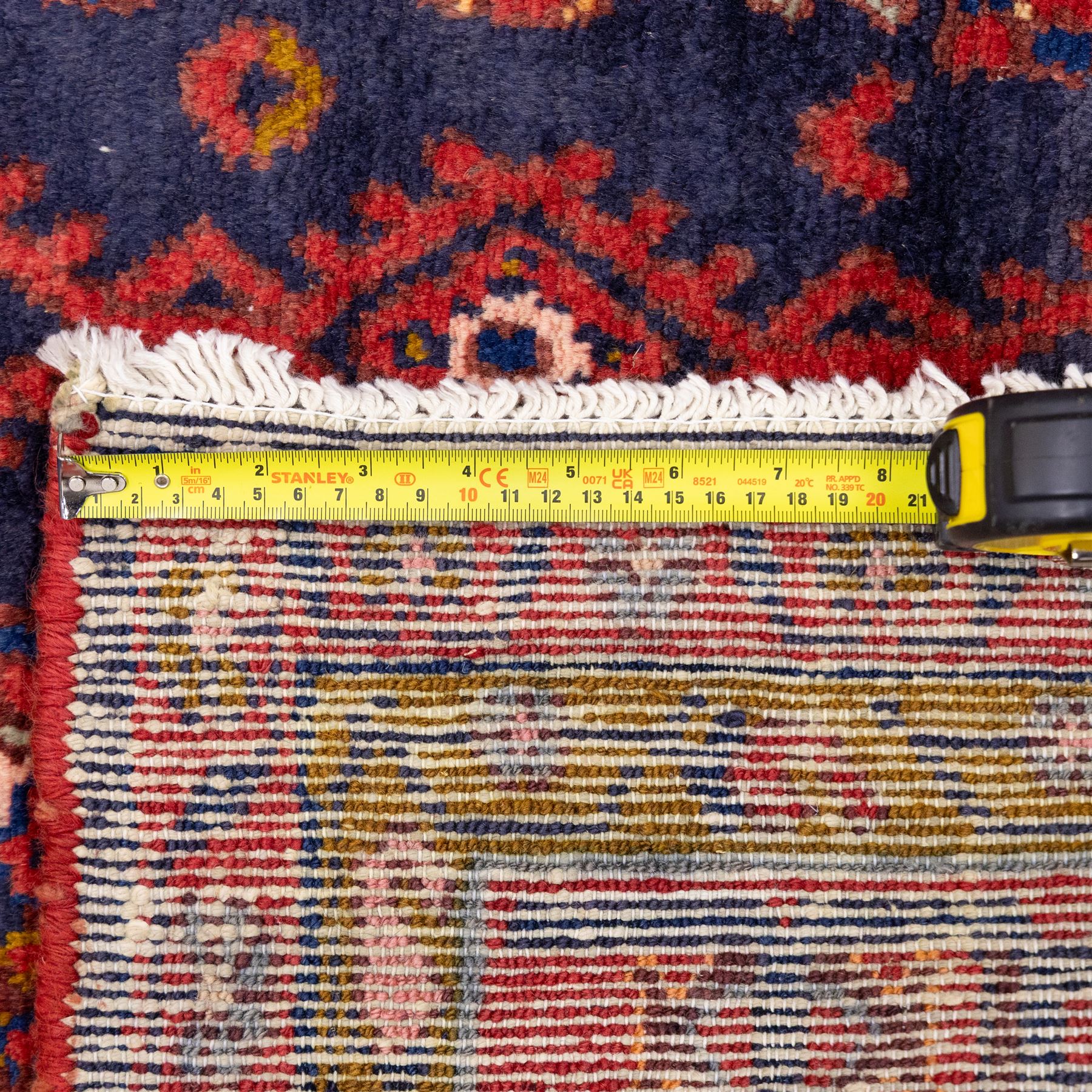 North West Persian Cirjan hand-knotted rug, indigo field decorated with vertical columns of stylized boteh, rosettes and diamond devices arranged in a repeating lattice and a chain of linked lozenges, enclosed by a mustard gold inner border and a principal border of madder ground, flanked by narrow guard stripes, with cotton fringe ends 