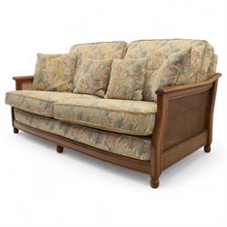 Ercol – bergère four piece suite, including armchair, two seat sofa, three seat sofa and footstool, all with removable floral upholstered cushions, the frames with side caning and rounded arm supports in stained beech

Three seat (H 87cm, D 89cm, W 196cm)
Two seat (H 87cm, D 89cm, W 137cm)
Armchair (H 87cm, D 89cm, W 87cm)
Footstool (H 28cm, D 55cm, W 55cm)