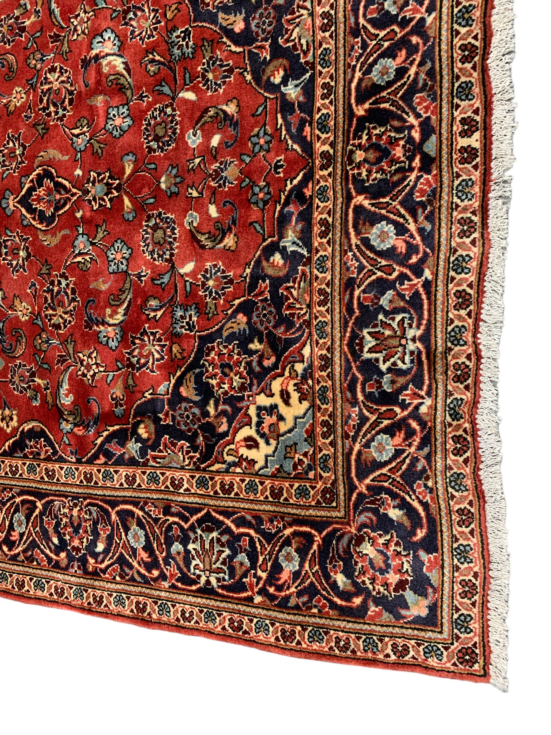 Persian Ardakan crimson ground rug, the field with shaped floral design medallion surrounded by curled leafy branches, scrolling border with stylised plant motifs