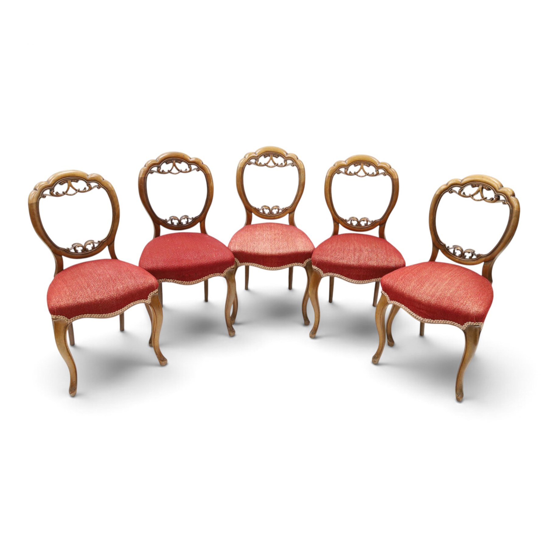Set of five Victorian mahogany dining chairs, the scalloped balloon back with pierced scrolling acanthus leaf decoration, sprung seats upholstered in crimson fabric, on cabriole supports