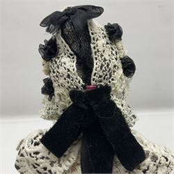 Anna Meszaros Hungary - hand made needlework figurine 'Old Lady' seated on a stool wearing a lace trimmed black/white/red floral full length dress and hat, working on a piece of lace H30cm  Auctioneer's Note: Anna Meszaros came to England from her native Hungary in 1959 to marry an English businessman she met while demonstrating her art at the 1958 Brussels Exhibition. Shortly before she left for England she was awarded the title of Folk Artist Master by the Hungarian Government. Anna was a gifted painter of mainly portraits and sculptress before starting to make her figurines which are completely hand made and unique, each with a character and expression of its own. The hands, feet and face are sculptured by layering the material and pulling the features into place with needle and thread. She died in Hull in 1998.