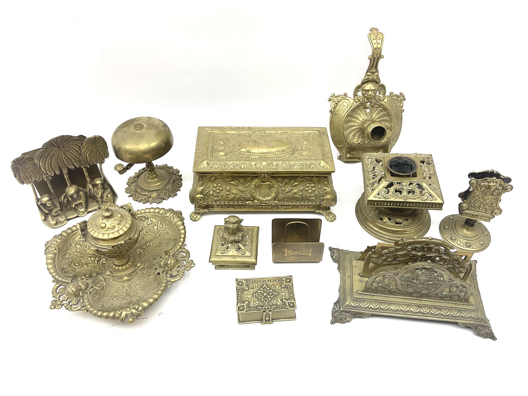 Collection of victorian and later brass desk accessories, to include a letter holder with cherub design, ink well of square form with hinged lid, brass table bell, brass casket with relief decoration, etc  