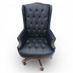 Chesterfield style desk chair upholstered in black, brass studded trim with tall button backed seat, with faux wooden base raised upon castors