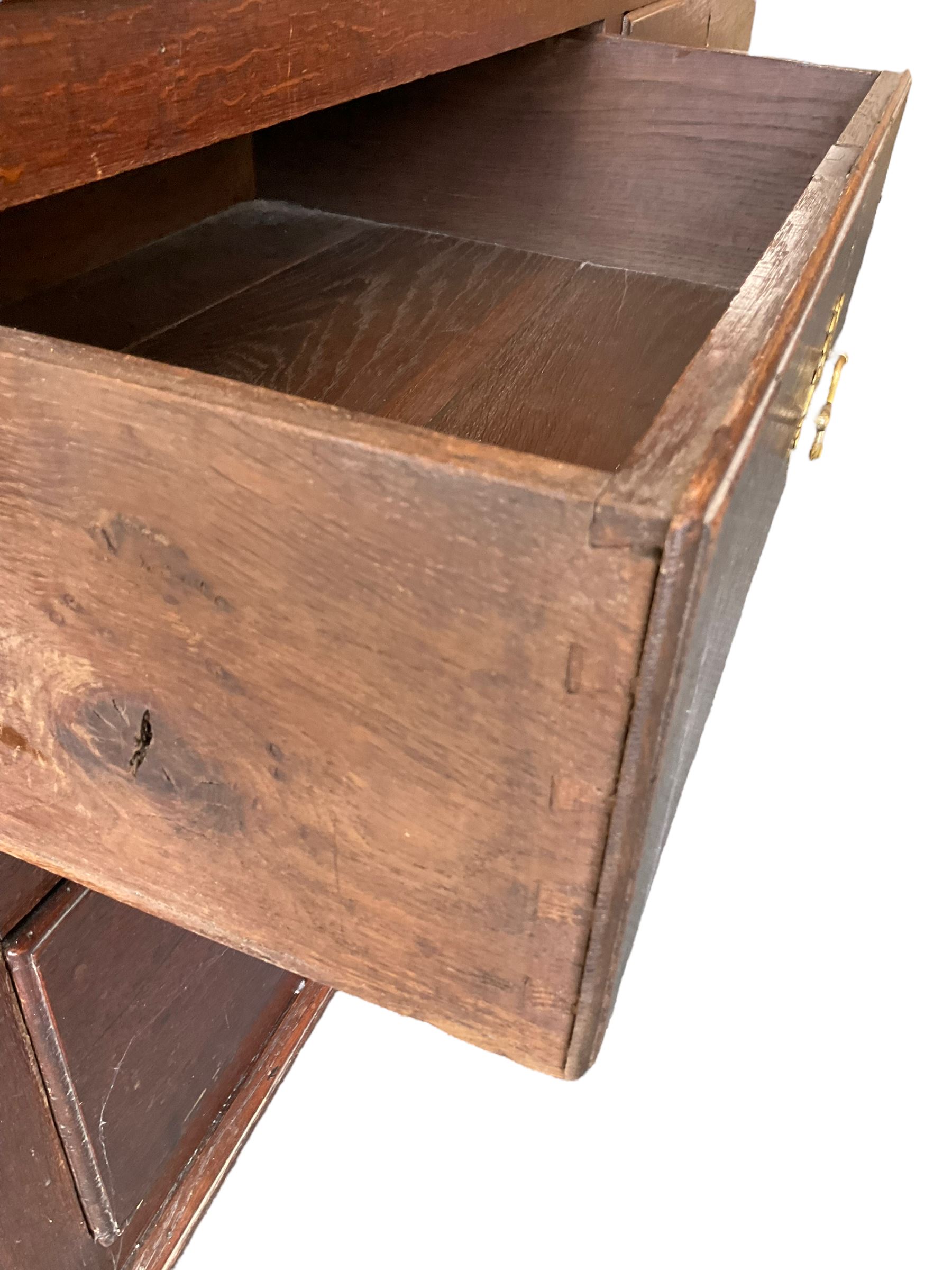 George III oak press cupboard, dentil cornice over two arch fielded panel doors, the base fitted with four drawers with pressed brass handle plates
