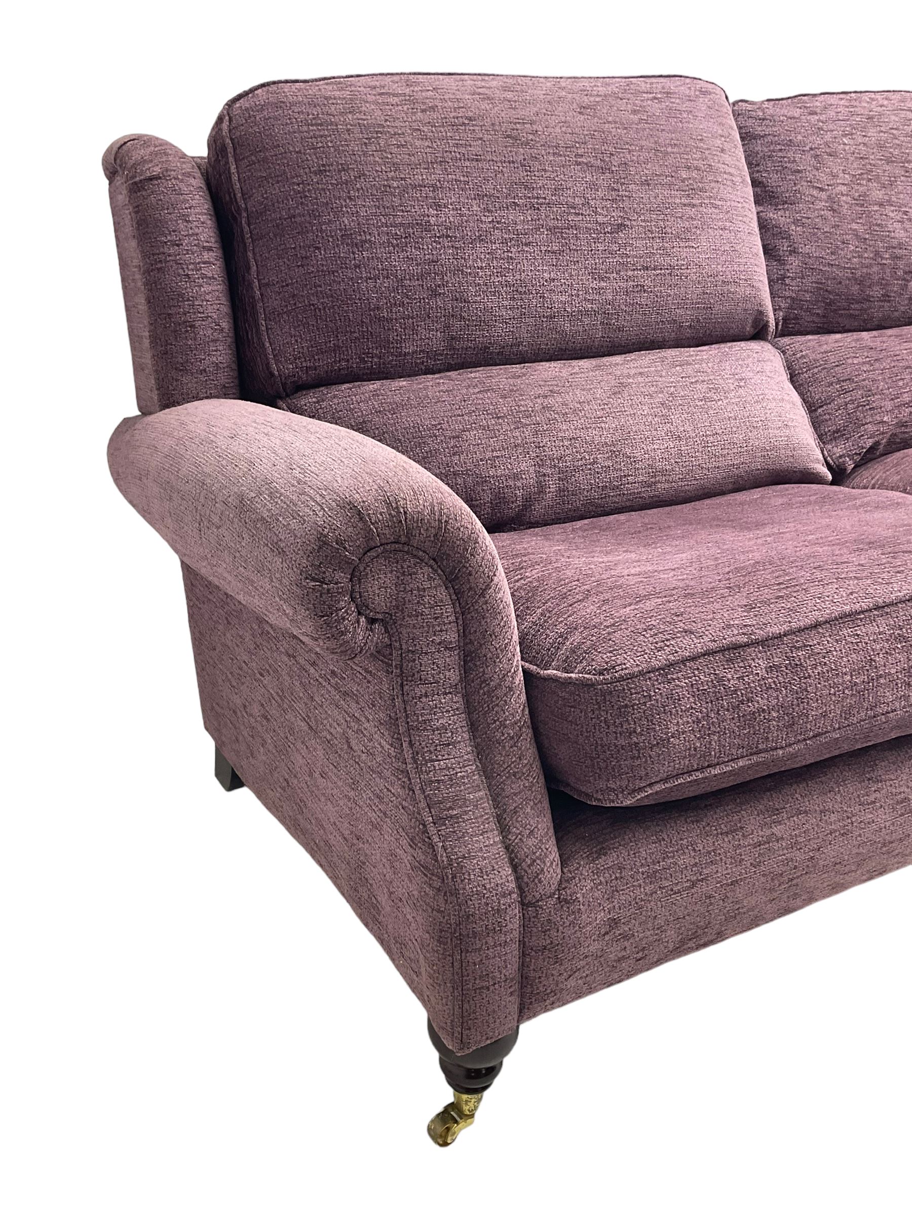 Parker Knoll - pair of large two-seat sofas upholstered in purple fabric, turned mahogany finish front feet with brass cups and castors 