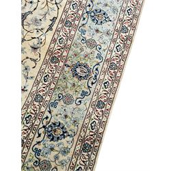 Persian Kashan ivory ground carpet, the field decorated with swirling foliate patterns and stylised plant motifs, scrolling border decorated with palmettes, within floral pattern guard stripes 