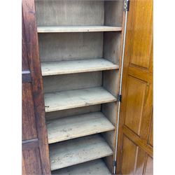 The North of England School Furnishing Company Limited Darlington - early 20th century oak school cupboard, projecting moulded cornice over two panelled doors, fitted with shelves, on chamfered plinth base 