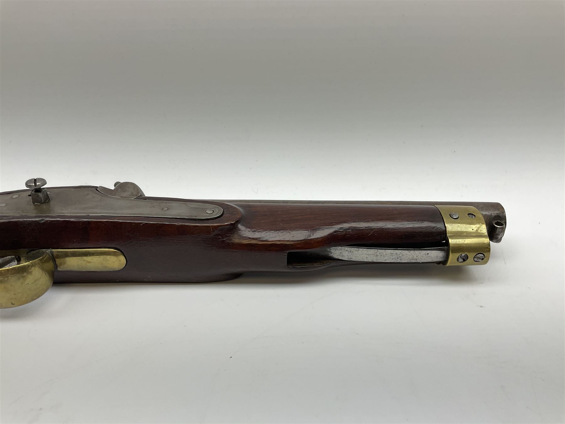 Early 19th century percussion cap cavalry pistol with round 23cm unsighted barrel, borderline engraved action lock (lacking hammer), walnut full stock with heavy brass furniture, iron lanyard ring to the flat butt cap and long flat retaining spring below fore-end for captive ramrod (missing) L41cm overall