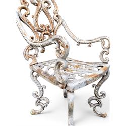 Pair of Victorian cast iron garden chairs, the ornate pierced back of scrolling foliate design, scrolling arm terminals over splayed supports formed of C and S-scrolls, in distressed white painted finish