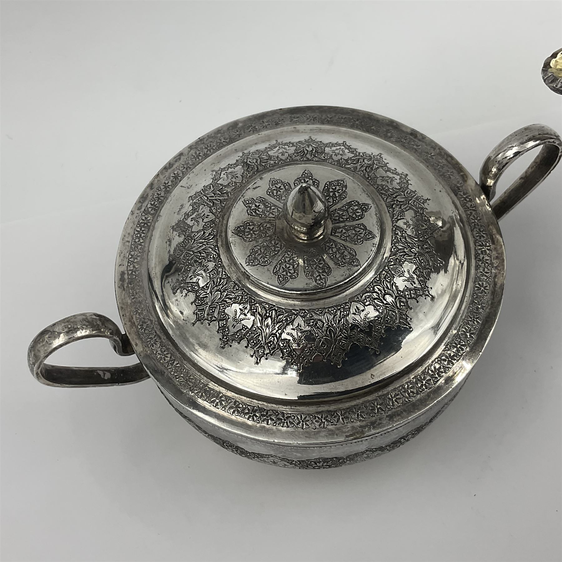Early/mid 20th century Persian silver tea service, comprising circular serving tray, teapot, twin handled sucrier and cover, milk jug, five tea glasses with six silver holders, six tea spoons, and pair of sugar tongs, each profusely chased with foliate arabesque decoration, each bearing marks including 84 for 840 fineness, tray D40cm, teapot H16cm