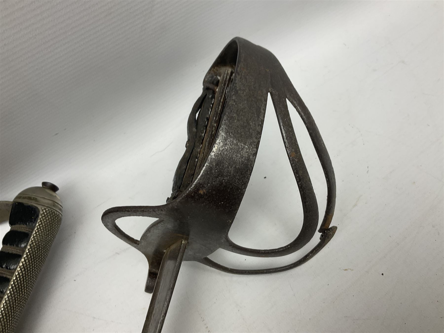 George V British Army 1897 pattern officers sword with plain 82cm fullered steel blade, pierced  basket hilt with George V cypher and wire bound leather grip with chequered backstrap; in leather covered field service scabbard L101cm overall; and another officer's sword in relic condition lacking scabbard (2)
