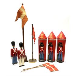 Five Kay Bojesen wooden soldiers, three boxed, two standard bearers with flags, one with gun, four with blue trousers and one white trousers H23cm, along with two table top Danish flags on flagpoles, mahogany flag pole H59.5cm and metal flagpole with a decorated base H39.5cm. 