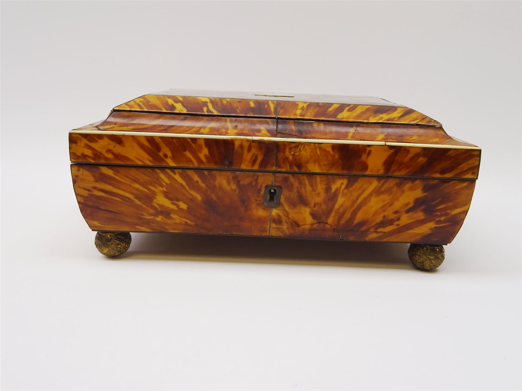 19th century tortoiseshell sewing box, of sarcophagal form upon four foliate detailed brass ball feet, the hinged cover edged in ivory with initialled silver plaque to centre, opening to reveal a silk lined interior, H9.5cm W22.5cm D18cm