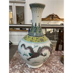 Pair 20th century Chinese famille verte bottle vases, each decorated with green and purple dragons chasing pearls amidst auspicious flames, the neck with yellow and green stylised foliate and cell borders, and the white glazed body incised throughout with fan shapes, each with red character mark beneath flanked by green dragons, H38cm

