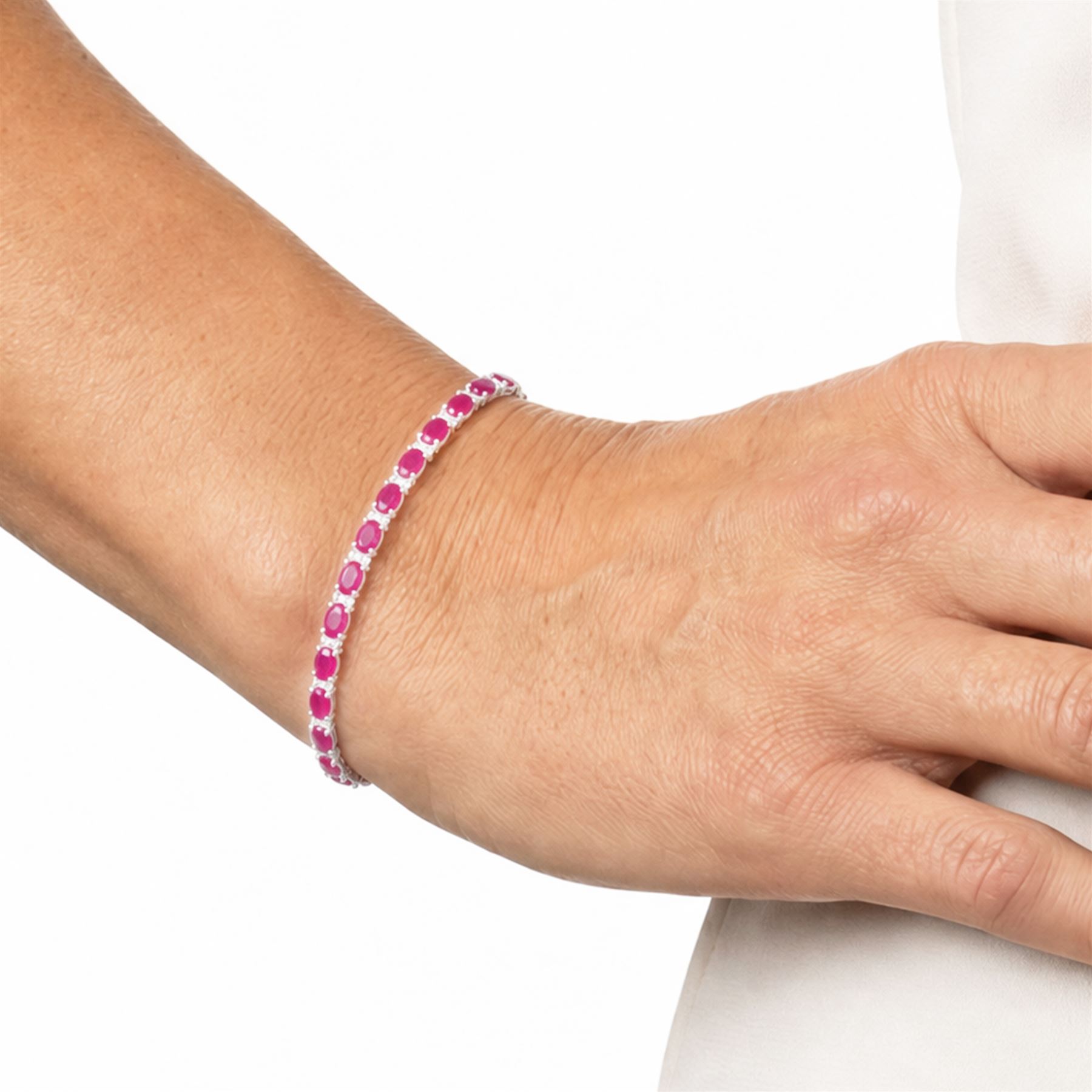 18ct white gold ruby and diamond bracelet, twenty-six oval cut rubies, each spaced by two round brilliant cut diamonds, hallmarked, total ruby weight approx 9.40 carat, total diamond weight 0.50 carat