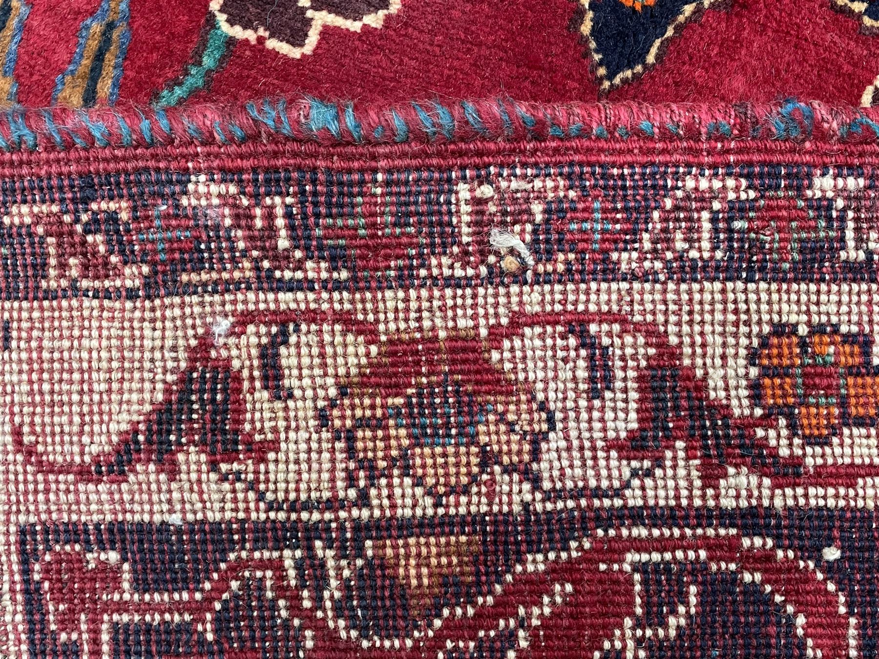 Persian rug, red ground field decorated with stylised flower heads and bird motifs, floral scrolling border