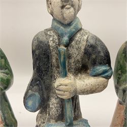 Three Chinese terracotta court attendant tomb figures, probably Ming Dynasty, two examples decorated in Sancai green glaze, the third example decorated in two tone blue glaze, each upon stepped square bases, tallest H22.7cm