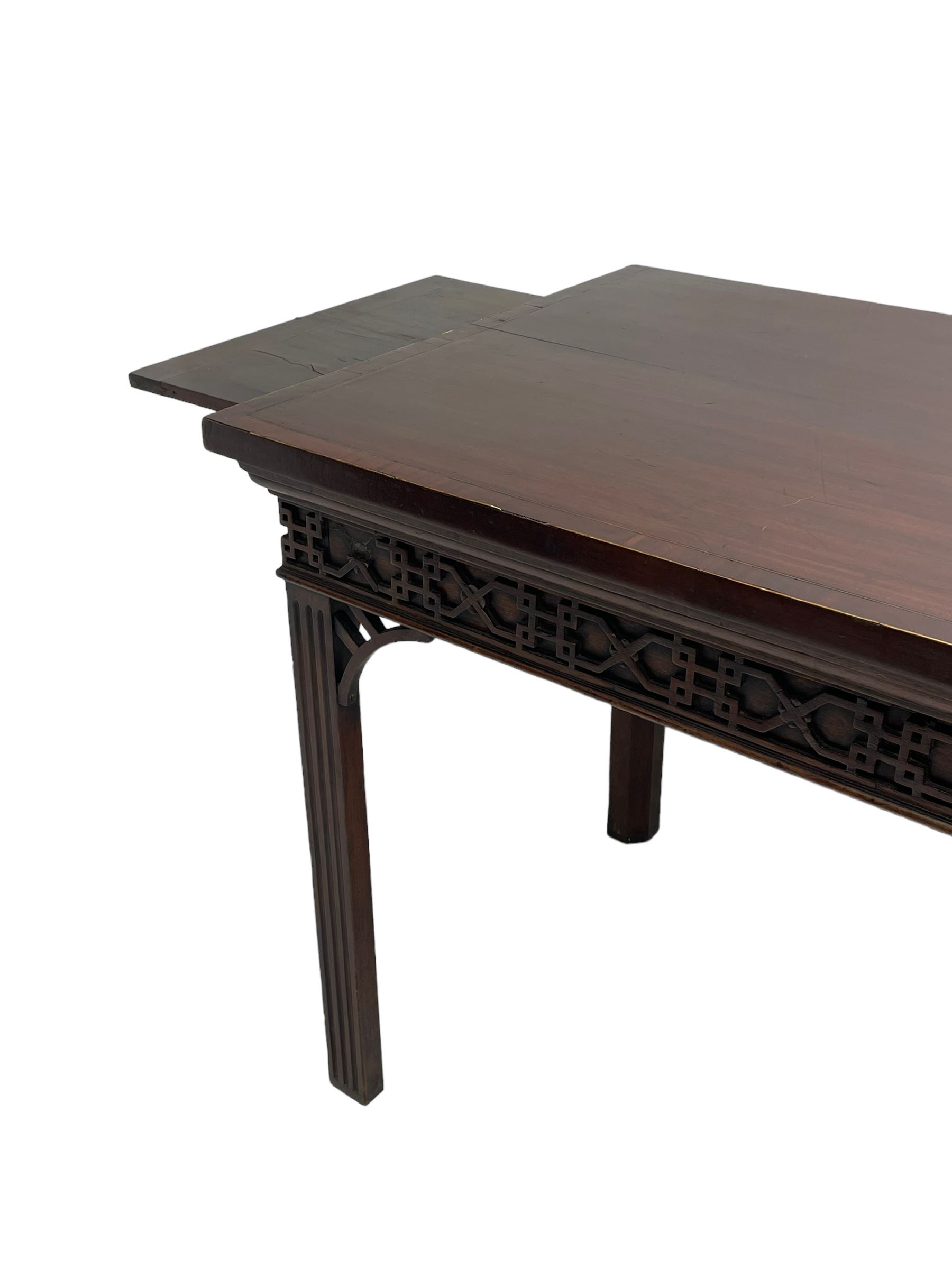 In the manner of Thomas Chippendale - early 19th century mahogany serving table, rectangular crossbanded top with boxwood stringing, the frieze with upper moulding over applied geometric fretwork, the left-hand side fitted with slide, on fluted square supports with inner chamfer 