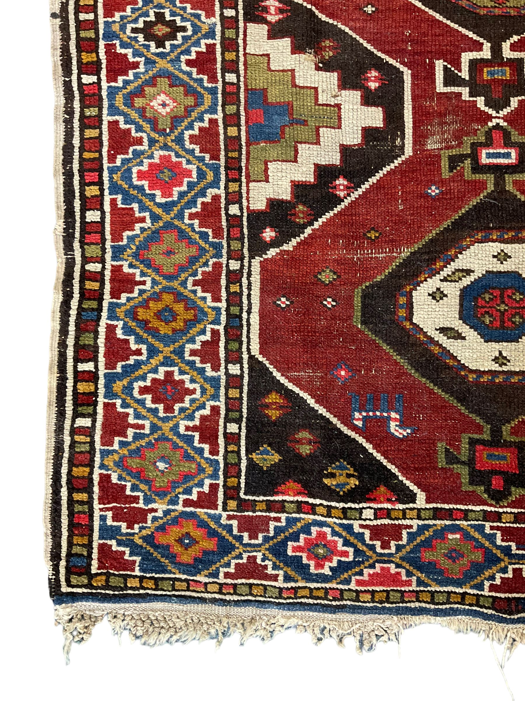 Anatolian Turkish red ground rug, decorated with three central lozenges, the multi-colour guarded border with repeating geometric shapes