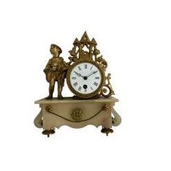 French alabaster and gilt spelter 8-day mantle clock with a drum timepiece movement on a raised rectangular alabaster base with scroll sidepieces, flanked by a figure of a young boy feeding a pet animal, white enamel dial with Roman numerals and steel moon hands. With pendulum.