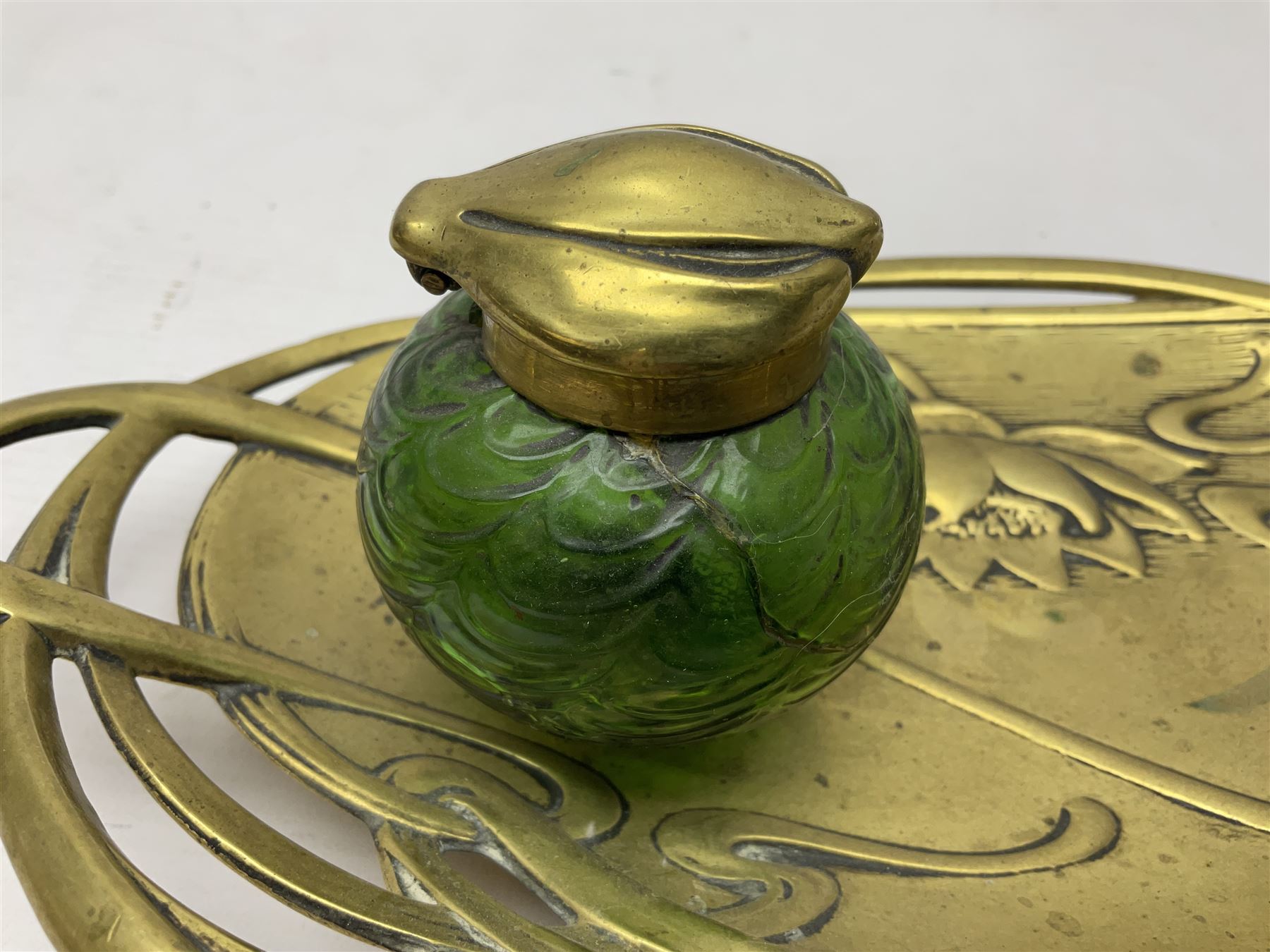 Art Nouveau Geschutzt brass desk stand, with stylised whiplash relief decoration, with removable Loetz style green glass inkwell, stamped to the base, H8cm