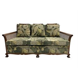 Early 20th century bergère lounge suite, mahogany framed with cane work back and sides, acanthus scroll carved uprights - three seat sofa (W167cm, H82cm, D83cm), and pair matching armchairs (W78cm), loose cushions upholstered in acanthus leaf scroll fabric with scatter cushions