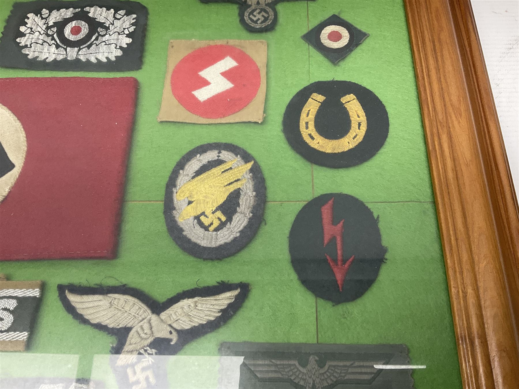 Framed display of thirty-four WWII German cloth badges including Luftwaffe pilot, Paratrooper, Afrikakorps cuff title, sleeve insignia for 'SS' Foreign Volunteers, various breast eagles including Luftwaffe, Army etc, RAD badges, Party Armband, rank and trade insignia, cap insignia etc; 40 x 50cm in modern pine frame