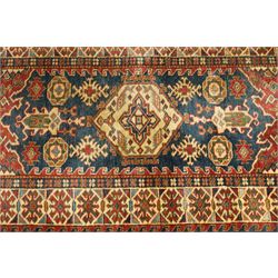 Caucasian hand-knotted runner, dark navy ground with three ivory geometric medallions surrounded by stylised flowerheads and angular motifs in madder red, green and ivory, enclosed by repeating geometric borders