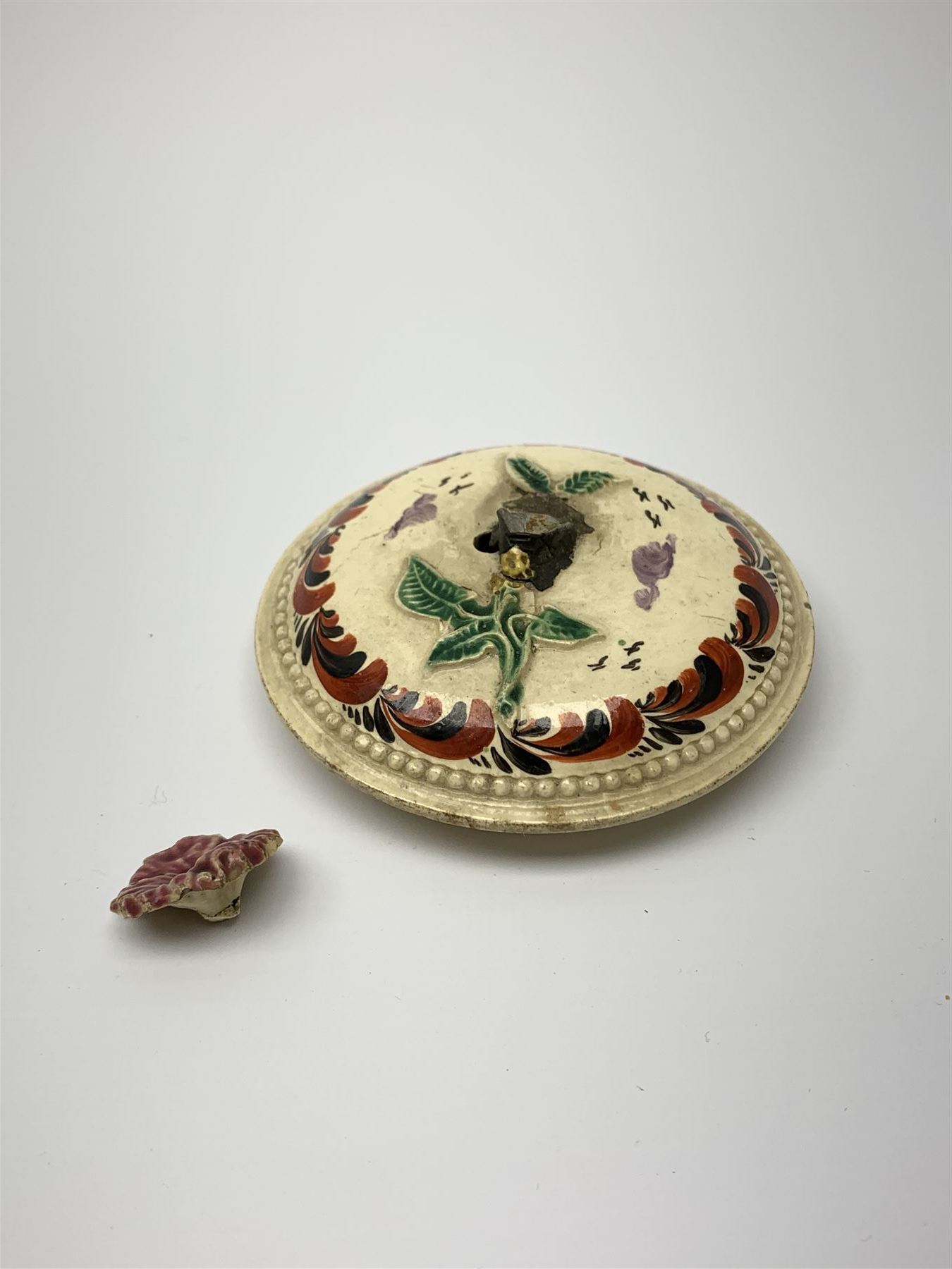 18th century creamware teapot, probably Leeds, with reeded entwined handle and floral finial to the cover, the body with hand painted polychrome decoration of figure to one side, and floral spray to the other, collectors paper label beneath inscribed Leeds Pottery, H11.5cm