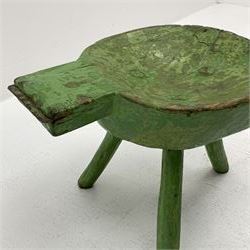 18th/19th century vernacular primitive green painted stool with dished seat fitted with metal scraper to one end, on three splayed legs, L46cm, H34cm