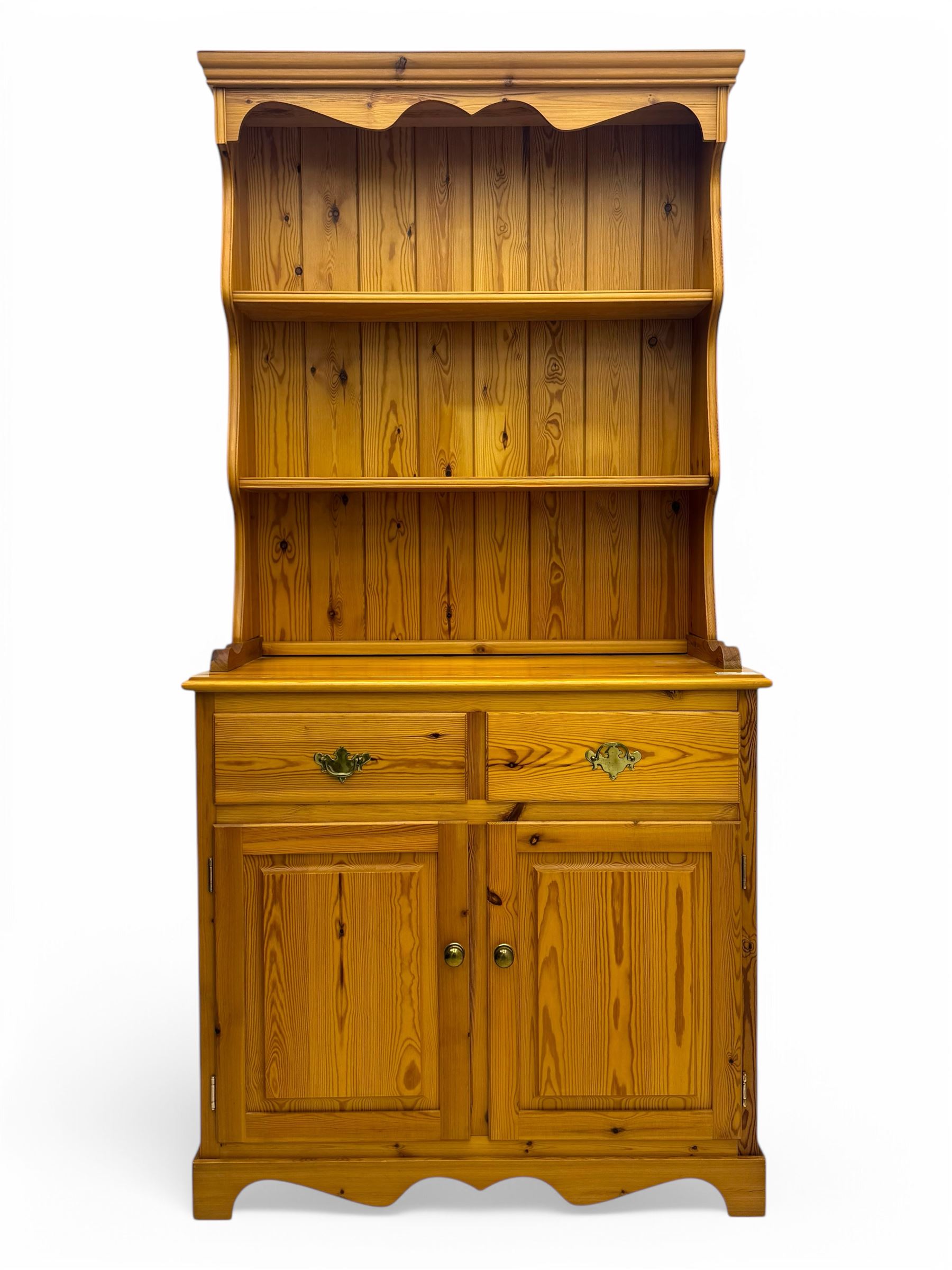 Victorian design pine dresser, projecting moulded cornice over scalloped frieze and two open shelves, base fitted with two drawers over double cupboard, on shaped plinth base