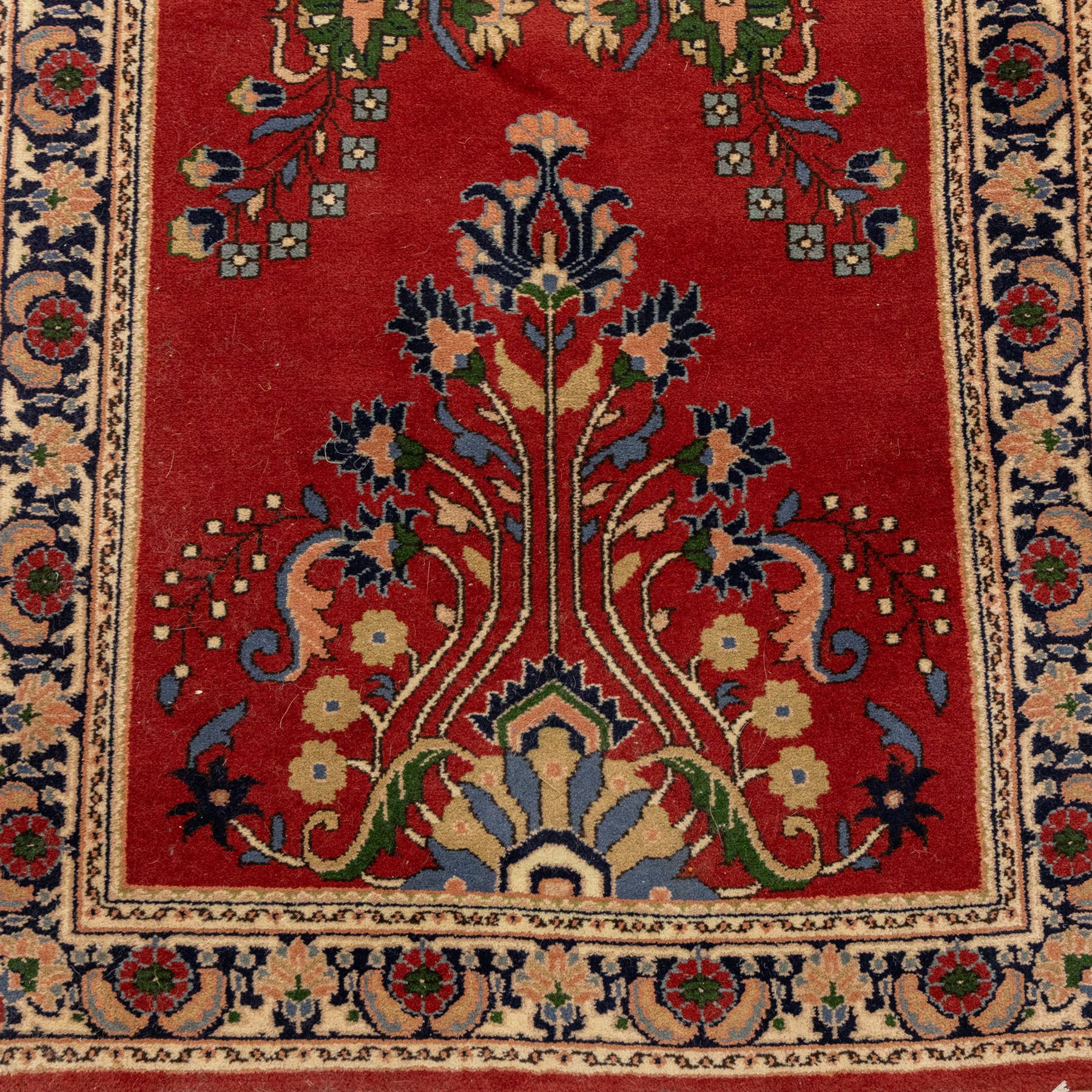 Kashan design wool runner, red field decorated with repeating floral medallions, palmettes and scrolling foliate motifs, enclosed by cream floral border and fringed ends