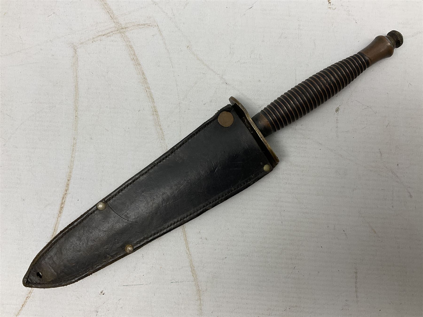 Fairburn and Sykes Commando fighting knife, 3rd pattern with 17cm double edged blade and copperised grip; no markings; in cut-down plain leather sheath L31.5cm