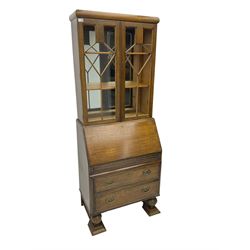 Early 20th century oak bureau bookcase, two astragal glazed doors enclosing two adjustable shelves with mirror back, fall-front concealing fitted interior over two drawers, raised on lobed baluster supports with stretcher base