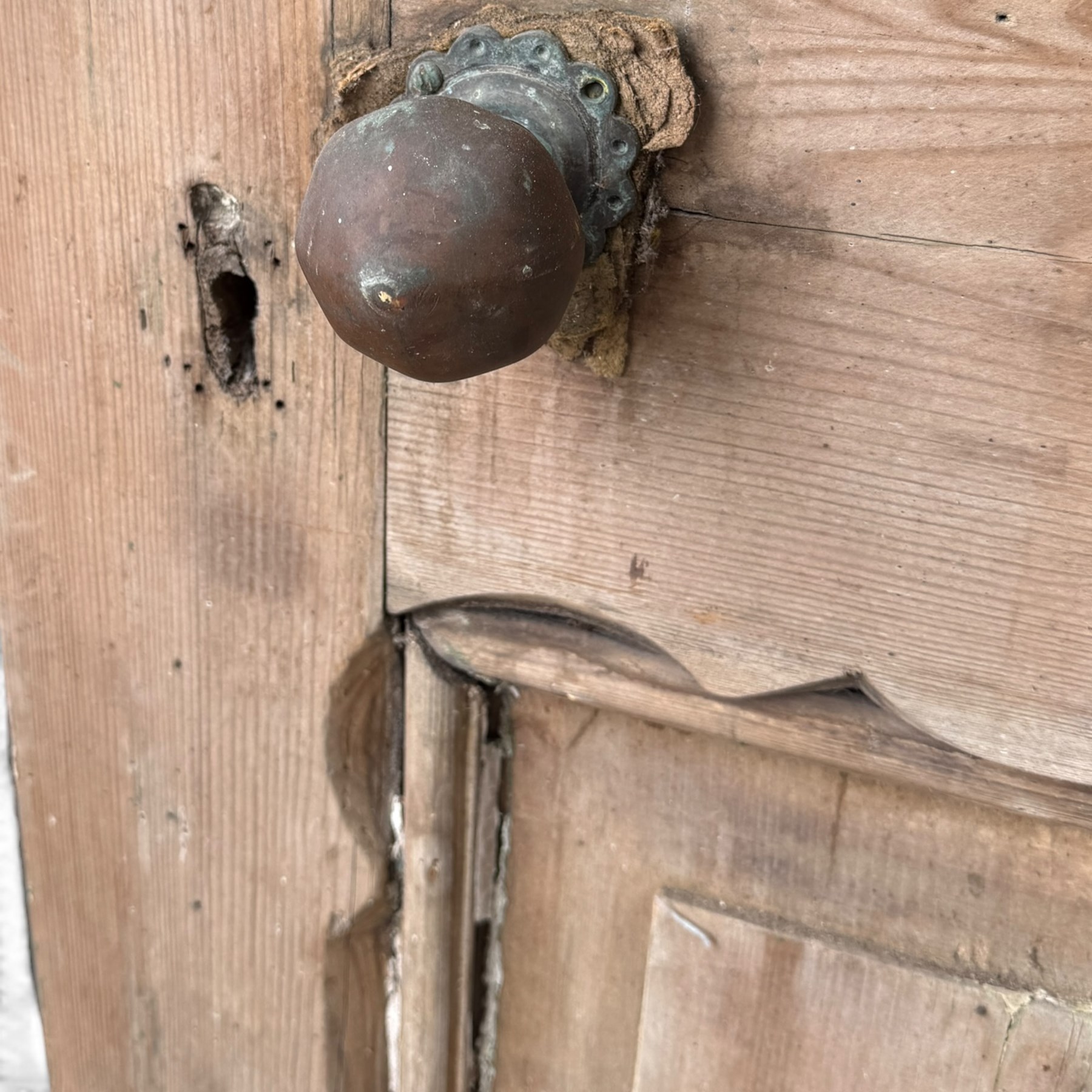 Victorian stripped pine four-panel door, the raised fielded panels within carved foliate and moulded surrounds, with iron lock and fittings and brass knob handle