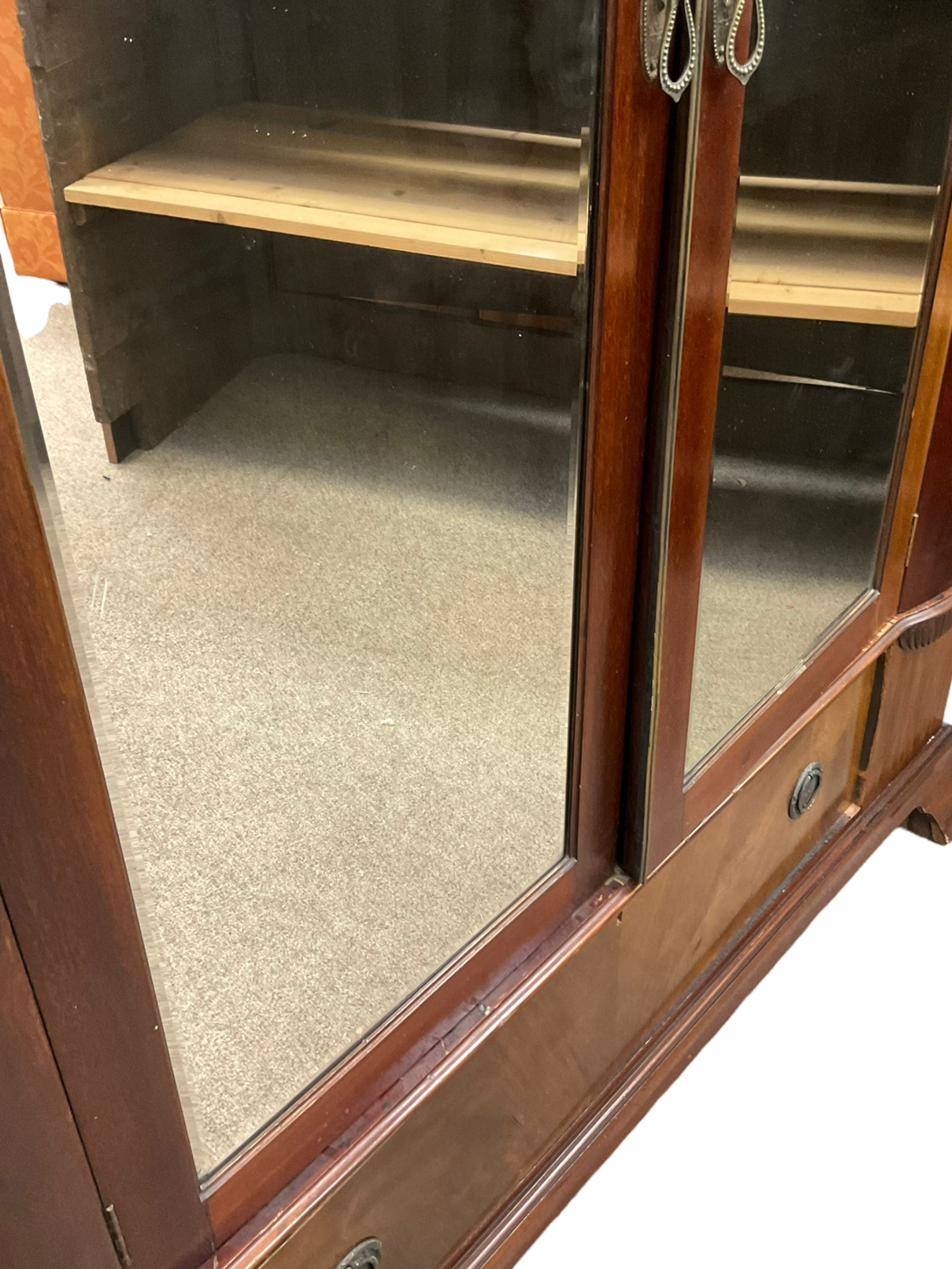 Late 19th century mahogany double wardrobe, projecting cornice over figured frieze, curved uprights enclosing two doors with bevelled mirrors, drawer to base, on splayed bracket feet