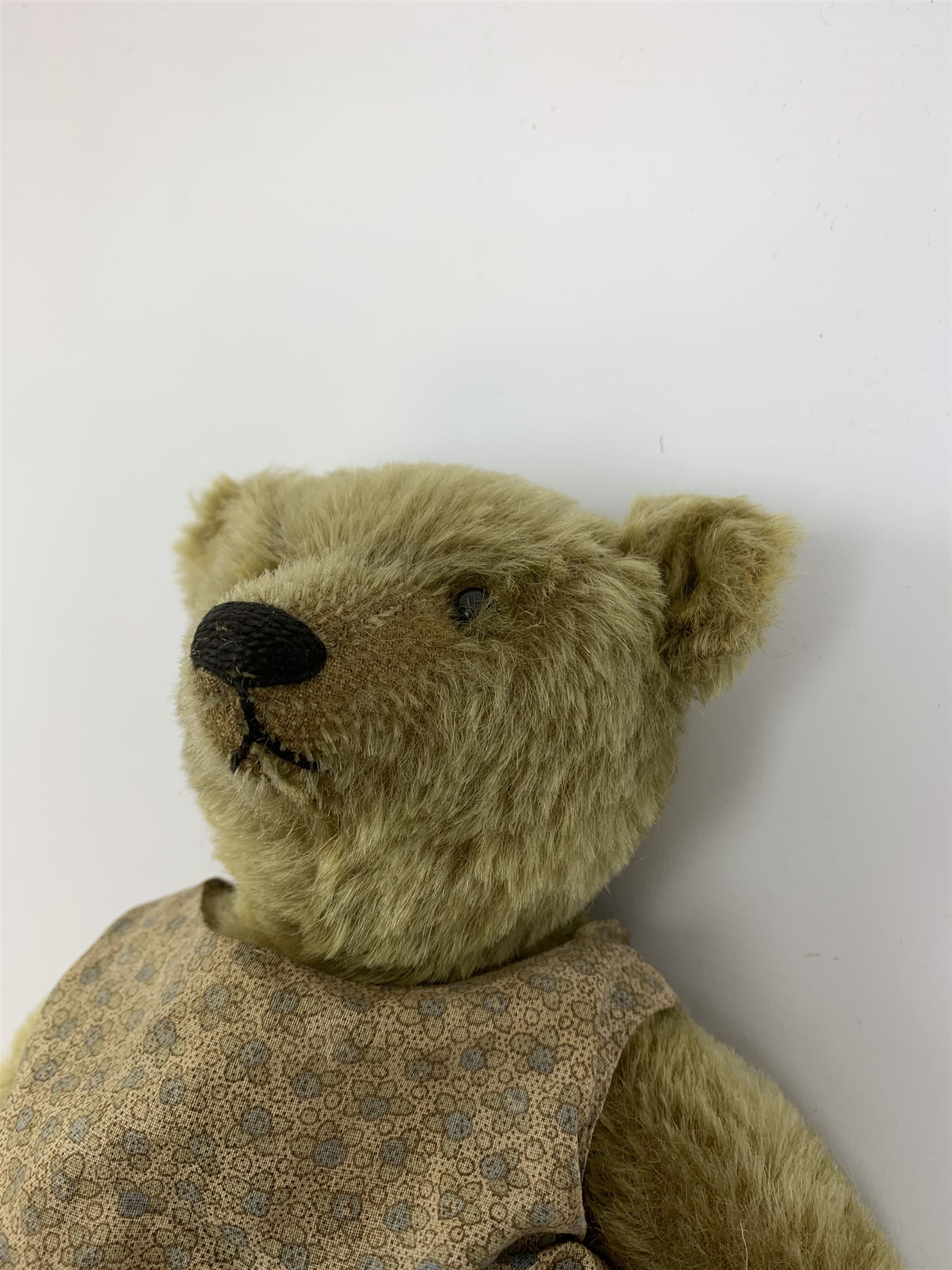 Early 20th century German Steiff teddy bear c1910 with wood wool filled humped back mohair body, swivel jointed head with black boot button eyes and horizontally stitched black nose and mouth, FF metal button to left ear, jointed elongated limbs with felt paw pads and black stitched claws H13