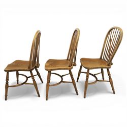 Traditional elm and beech Windsor dining chairs, each with hoop back and turned spindles over a shaped solid seat fitted with loose floral upholstered cushions, raised on turned tapering supports united by crinoline stretchers