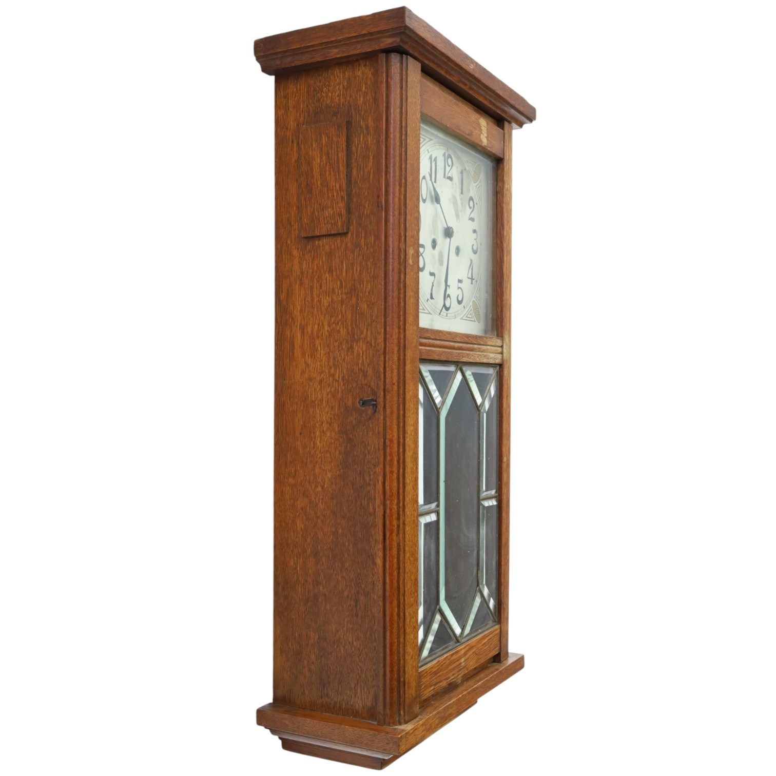 Art Deco style oak wall clock, moulded cornice above a silvered dial with Arabic numerals and geometric spandrels, glazed door with geometric bevelled glass panels enclosing a circular pendulum, on a stepped moulded base
