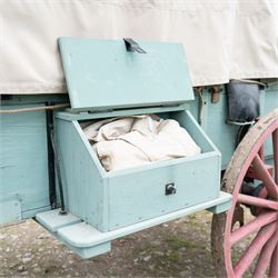 Western Covered Chuck Wagon

A large four wheeled covered wagon of timber construction, painted pale green with red painted wooden spoked wheels and a cream canvas tilt over an arched frame. The wagon has a traditional box body with covered rear compartment, front driving position, underbody turntable steering and iron fittings throughout. Fitted with external equipment details including a side mounted barrel, lidded storage chest, rope tie downs, horseshoe fittings and rear storage box.

Features

• Pale green painted timber body
• Cream canvas tilt over arched frame
• Covered rear compartment
• Front driving position
• Side mounted barrel
• External lidded storage chest
• Rear storage box
• Wooden spoked wheels
• Iron tyres
• Underbody turntable steering
• Rope tie downs
• Horseshoe fittings
• Iron hardware and brackets
• Brass restoration plaque to rear

Dimensions:
Overall length: 335 cm
Width: 170 cm
Height: 275 cm

Wheel Diameters:
Front wheels: 92 cm
Rear wheels: 112 cm

Seating:
Driver: 1
Passenger: Rear covered compartment