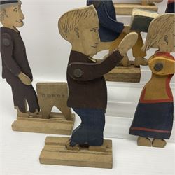 Eleven late19th/early 20th century partially painted fretworked wooden figures of children and various age adults, all with articulated arms, some standing or seated reading a book, seven loose mounted on grooved wooden bases, tallest H18cm