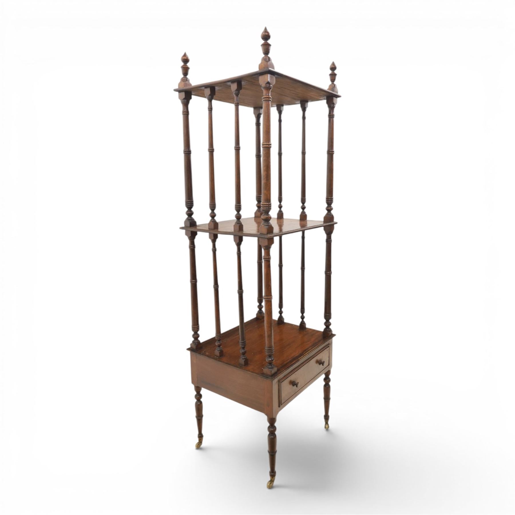 Late Victorian mahogany whatnot, the three tiers supported by turned spindle uprights with turned finials, fitted with a single frieze drawer, raised on turned supports with brass castors