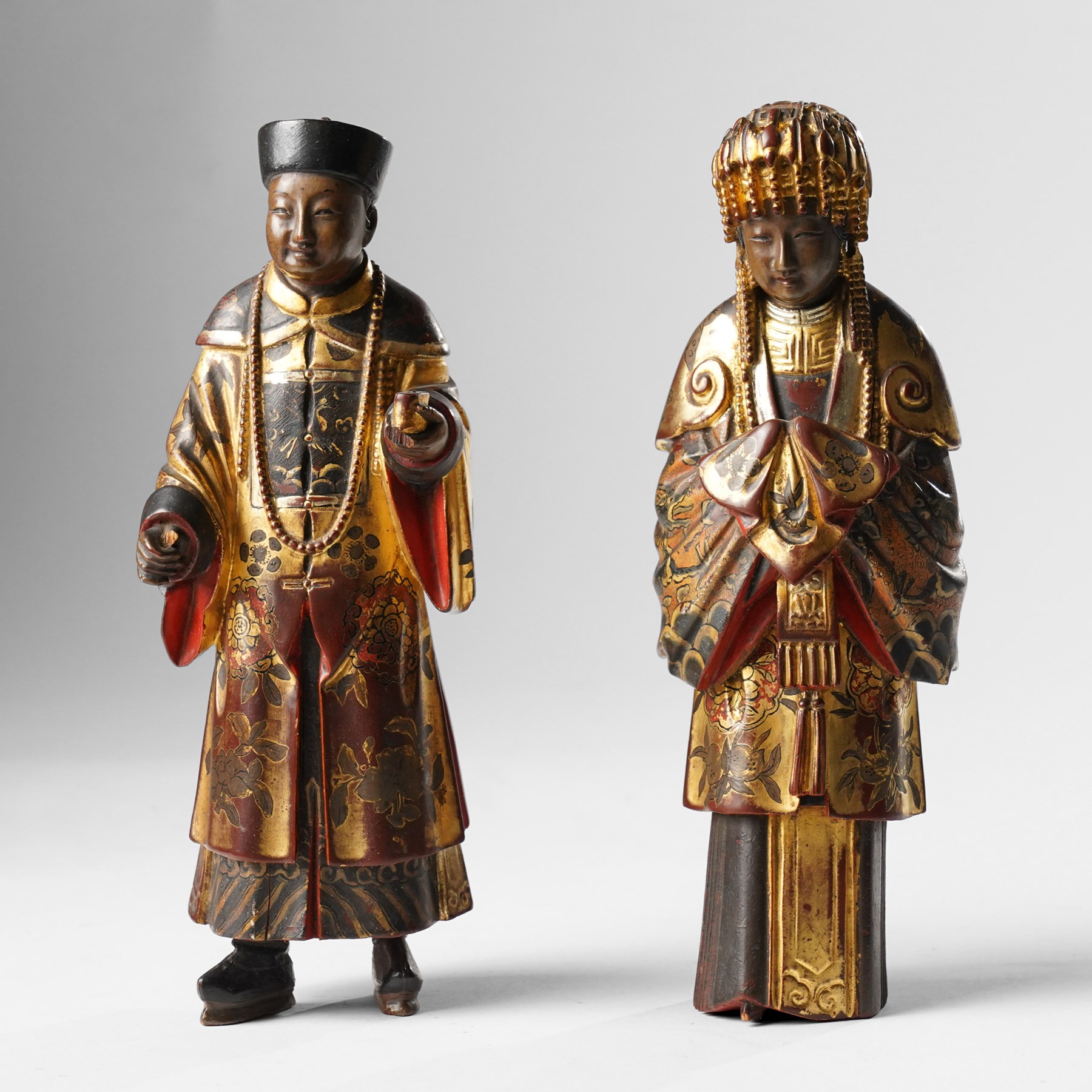 Pair of Chinese carved wooden lacquered figures, in ceremonial dress, possibly wedding attire, highlighted throughout in gilt, H22cm