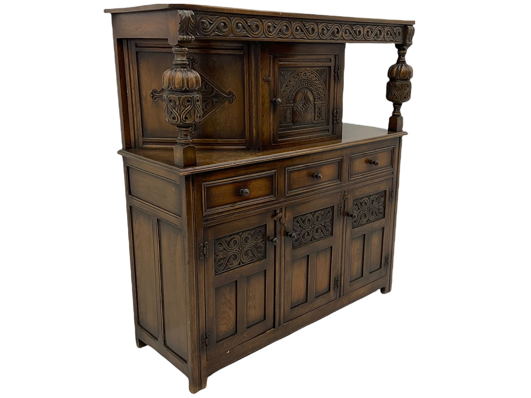 20th century carved oak court cupboard, s-scroll carved frieze over panelled cupboard door carved with arch, lobe and scroll carved cup and cover supports, fitted with three drawers and three cupboards below