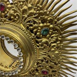20th century gilt metal monstrance, in the Gothic revival style, with glazed aperture to centre surrounded with clear paste stones, in a pierced floral and scroll border set with coloured paste stones, within a sunburst surround, on a paste set knopped stem and similar foliate foot, H59.3cm