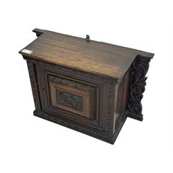 18th century and later carved oak cupboard, enclosed by panelled door carved with central bird motif and scrolled leafage with an outer ebony band, the frieze and uprights carved with repeating lunette and floral designs, flanked by scrolled foliate carved upright brackets
