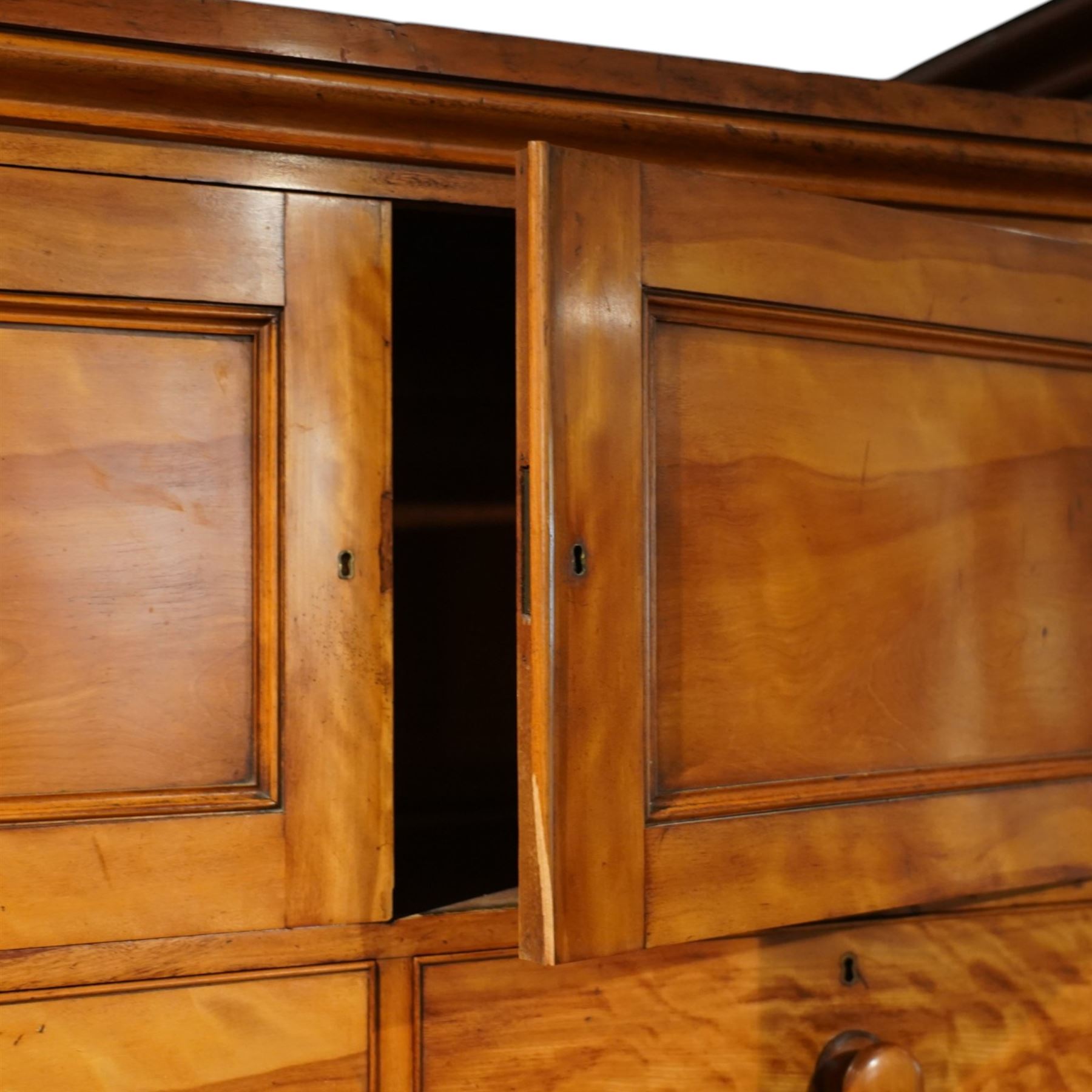 Victorian satinwood reverse breakfront triple wardrobe, projecting moulded cornice over twin full-length panelled cupboard doors flanking central linen press section, fitted with two cupboard doors above two short and four long drawers, turned wooden handles and moulded plinth base