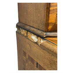 Late 19th century continental oak commode, serpentine fronted with parquetry and crossbanded decoration, the raised superstructure back fitted with a central bank of five recessed drawers flanked by concave drawers, above three full-width drawers with brass ring handles, raised on cabriole supports