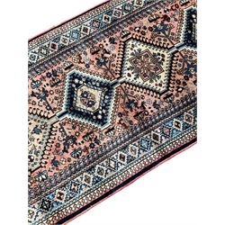 Persian Yalameh coral ground runner rug, the field decorated with seven hooked lozenge medallions surrounded by stylised plant motifs, the indigo spandrels decorated with similar patterns, guarded border with repeating diamond lozenges