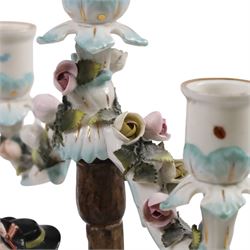 Pair of 19th Century German three-branch figural candlesticks, the figures each in floral dress against a tree, the branches decorated in relief with roses and the sconces painted with insects, H33cm 